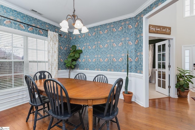 dining area with crown molding, a chandelier, and light hardwood / wood-style flooring