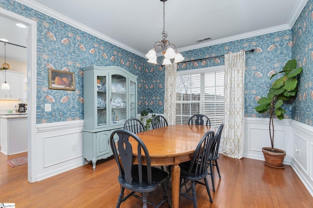 dining area featuring crown molding, a chandelier, and light hardwood / wood-style floors