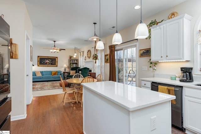 kitchen featuring pendant lighting, white cabinets, hardwood / wood-style flooring, a center island, and stainless steel dishwasher