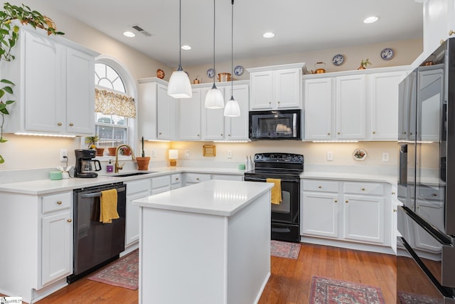 kitchen featuring hanging light fixtures, black appliances, a center island, and white cabinets