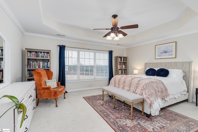 carpeted bedroom with ceiling fan, ornamental molding, and a raised ceiling