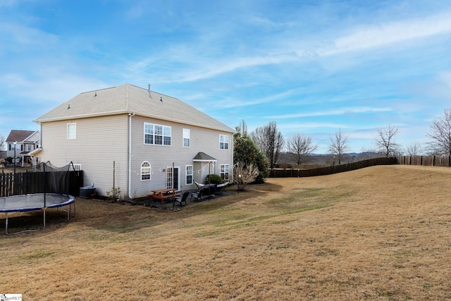 rear view of house featuring a yard and a trampoline