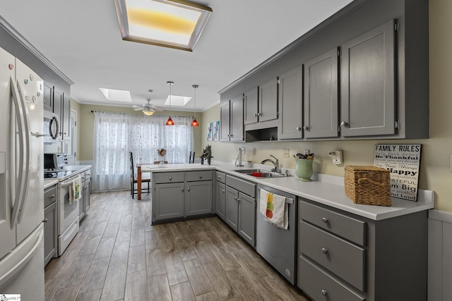 kitchen with gray cabinets, appliances with stainless steel finishes, hanging light fixtures, a skylight, and kitchen peninsula