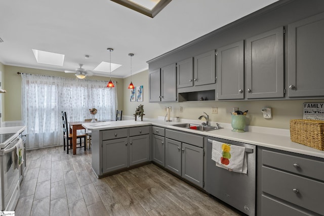 kitchen with sink, gray cabinets, a skylight, decorative light fixtures, and stainless steel dishwasher