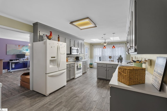 kitchen featuring white appliances, hardwood / wood-style flooring, gray cabinets, a skylight, and decorative light fixtures