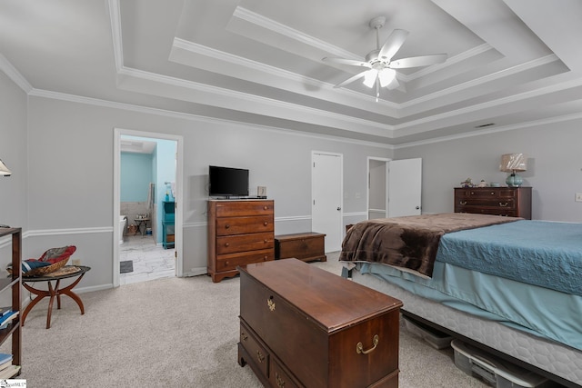 carpeted bedroom with crown molding, connected bathroom, ceiling fan, and a tray ceiling