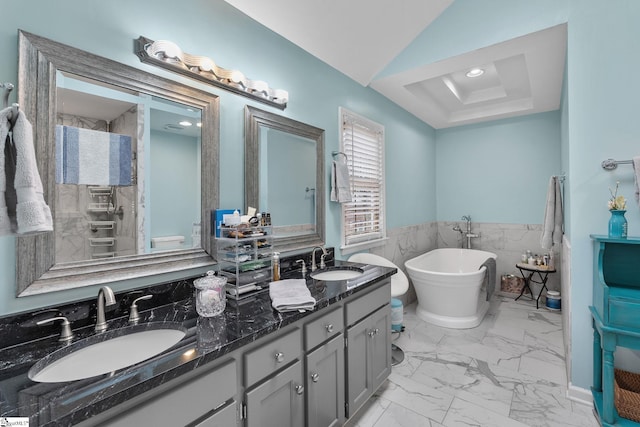 bathroom with a washtub, vanity, lofted ceiling, and tile walls