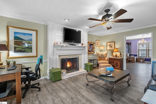 living room featuring hardwood / wood-style flooring, a fireplace, ornamental molding, and ceiling fan with notable chandelier