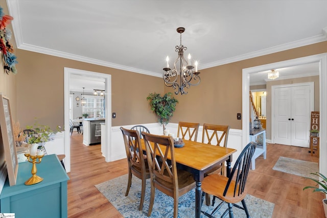 dining area with ornamental molding, a chandelier, and light wood-type flooring