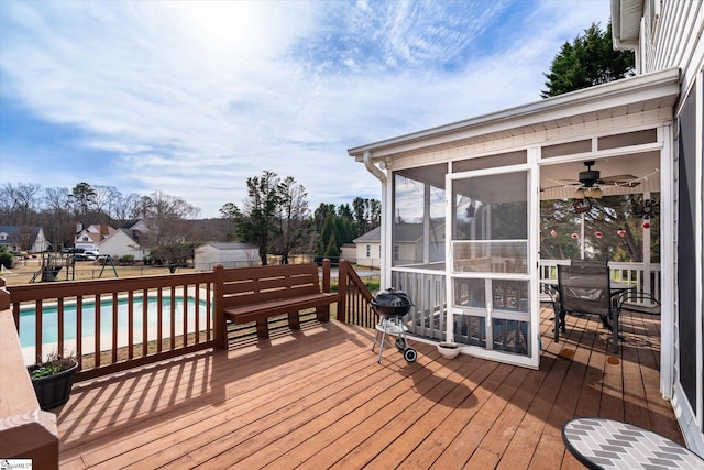 wooden terrace with a fenced in pool, a sunroom, and ceiling fan