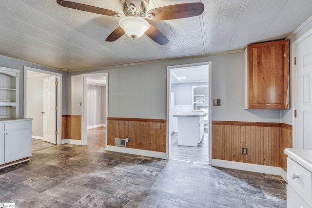 kitchen featuring ceiling fan, wooden walls, and a textured ceiling