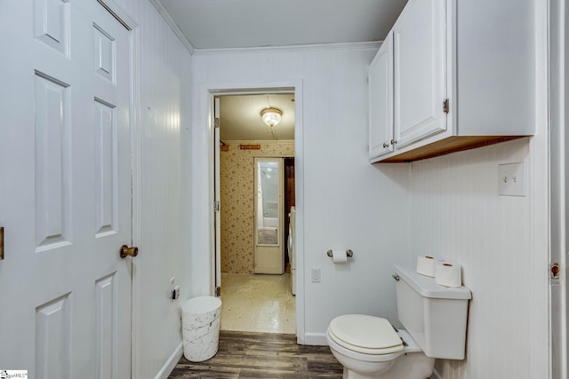 bathroom with crown molding, toilet, and hardwood / wood-style flooring