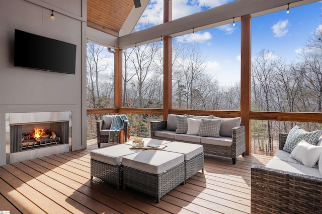 sunroom / solarium featuring lofted ceiling, exterior fireplace, and ceiling fan