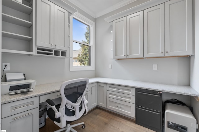 office space featuring hardwood / wood-style floors, crown molding, and built in desk