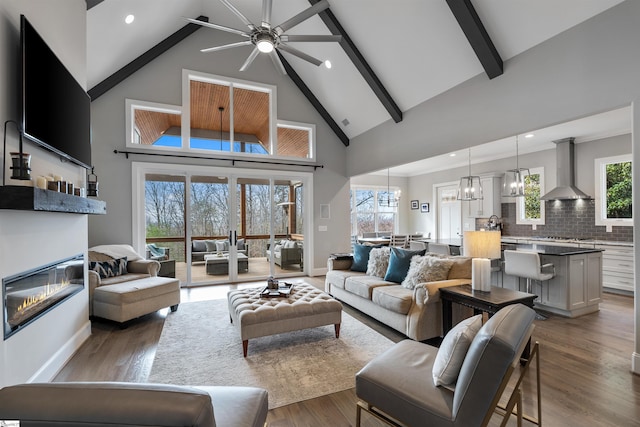 living room with an inviting chandelier, beam ceiling, dark wood-type flooring, and a wealth of natural light