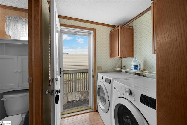 clothes washing area with cabinets, ornamental molding, independent washer and dryer, a textured ceiling, and light hardwood / wood-style flooring