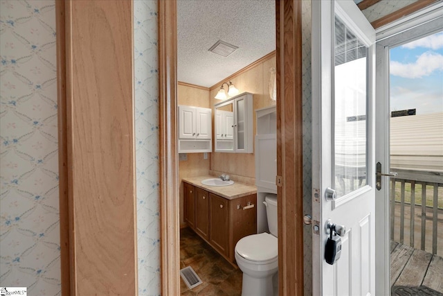 bathroom featuring ornamental molding, vanity, toilet, and a textured ceiling