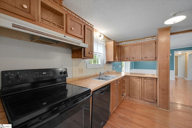 kitchen featuring sink, a textured ceiling, light wood-type flooring, and black appliances