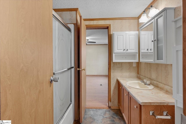 bathroom featuring vanity, crown molding, shower / bath combination with glass door, and a textured ceiling