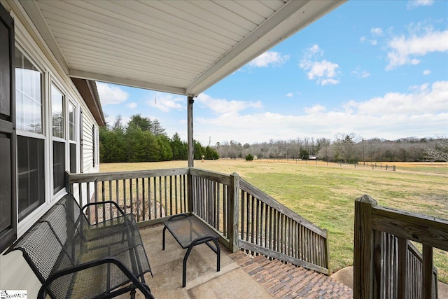 wooden terrace with a rural view and a yard