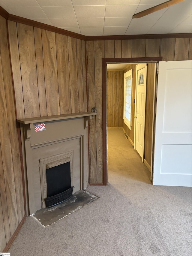 unfurnished living room featuring wooden walls, a fireplace, and light carpet