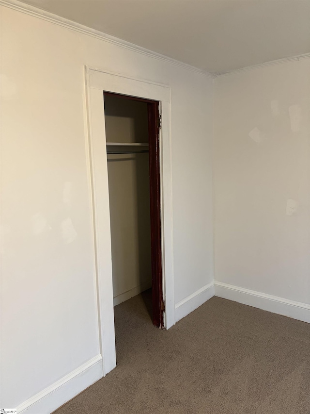 unfurnished bedroom featuring crown molding, carpet flooring, and a closet