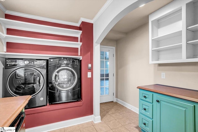 washroom with crown molding, washing machine and clothes dryer, and light tile patterned floors