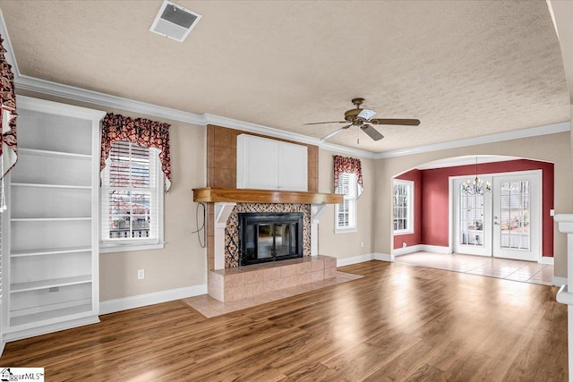 unfurnished living room featuring ornamental molding, hardwood / wood-style floors, a tile fireplace, and a textured ceiling