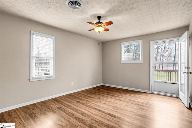 unfurnished room with a textured ceiling, ceiling fan, and light wood-type flooring