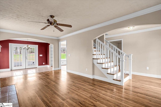 interior space featuring ceiling fan with notable chandelier, hardwood / wood-style floors, ornamental molding, a textured ceiling, and french doors