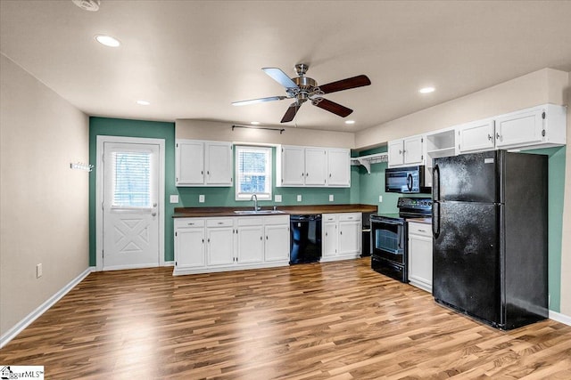 kitchen featuring white cabinetry, sink, light hardwood / wood-style floors, and black appliances