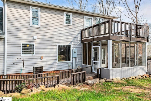 rear view of property featuring a wooden deck, a sunroom, and central AC unit