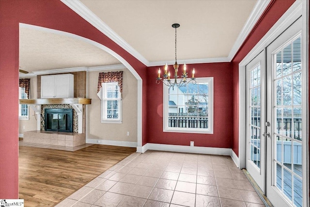 unfurnished dining area featuring ornamental molding, a high end fireplace, wood-type flooring, and a notable chandelier