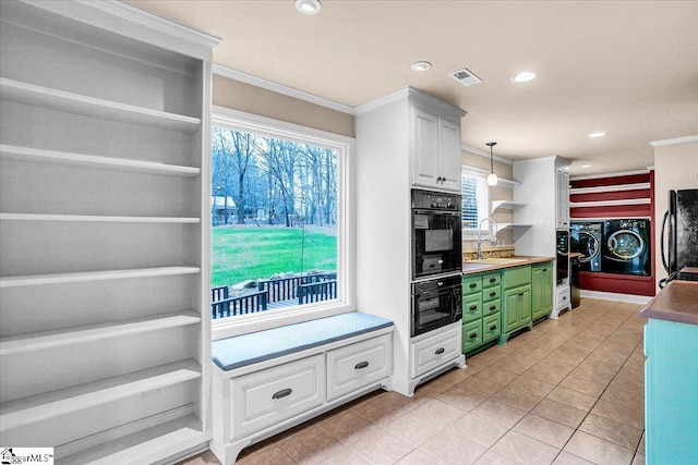 kitchen featuring sink, washer and clothes dryer, white cabinetry, hanging light fixtures, and black fridge