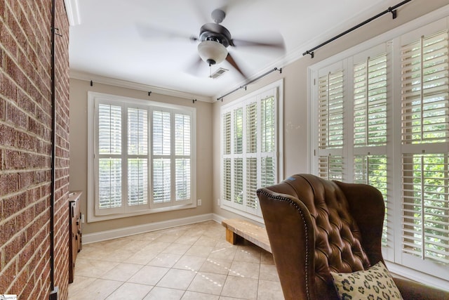 sitting room with light tile patterned floors, crown molding, ceiling fan, and brick wall