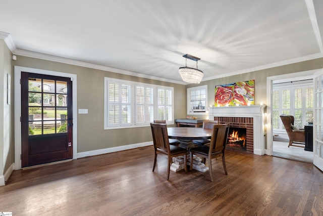 dining area featuring dark hardwood / wood-style flooring, a notable chandelier, crown molding, and a fireplace