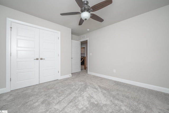 unfurnished bedroom with light colored carpet, a closet, and ceiling fan