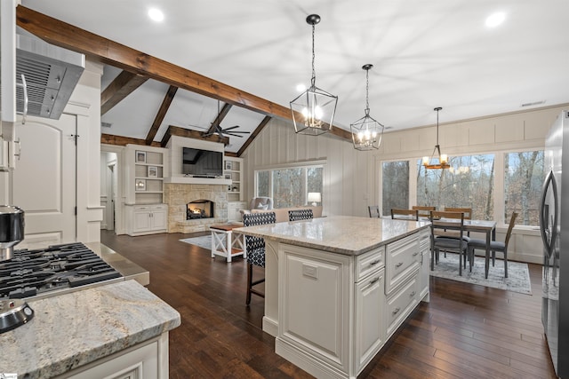 kitchen with a center island, white cabinets, a fireplace, and decorative light fixtures