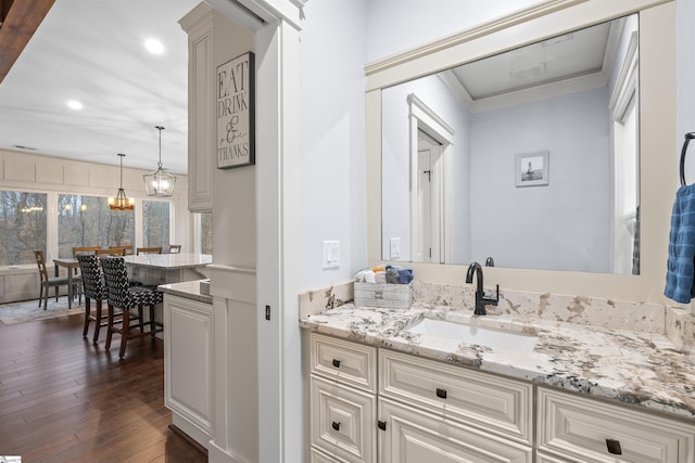 bathroom featuring ornamental molding, wood-type flooring, a notable chandelier, and vanity