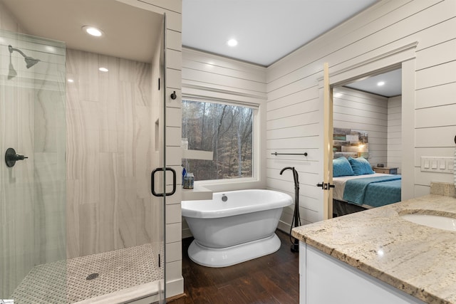 bathroom with vanity, wood-type flooring, wooden walls, and separate shower and tub