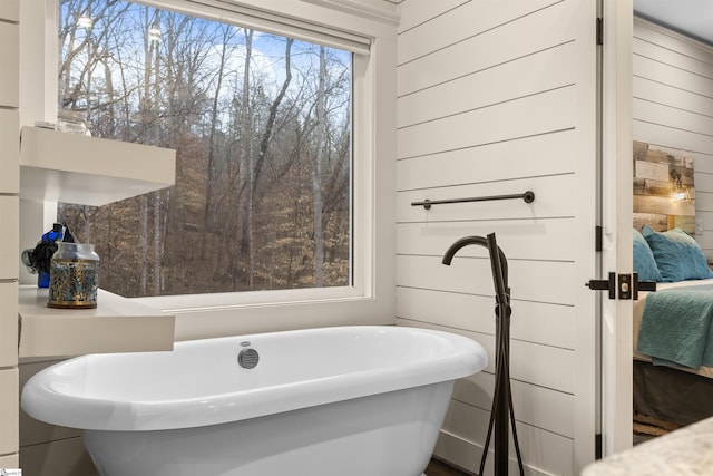 bathroom featuring a tub to relax in and wood walls