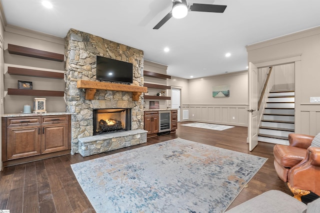 living room featuring wine cooler, a stone fireplace, dark hardwood / wood-style flooring, and ornamental molding