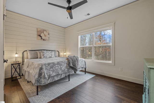 bedroom featuring crown molding, dark hardwood / wood-style floors, ceiling fan, and wood walls