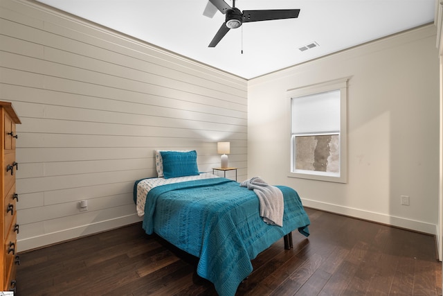 bedroom with dark wood-type flooring, ceiling fan, ornamental molding, and wooden walls