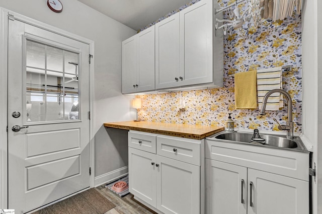 kitchen with tasteful backsplash, wooden counters, sink, and white cabinets