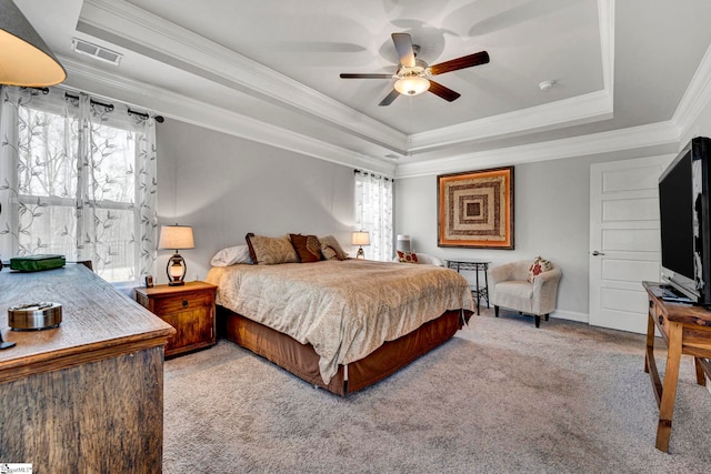 bedroom with a raised ceiling, crown molding, light colored carpet, and multiple windows