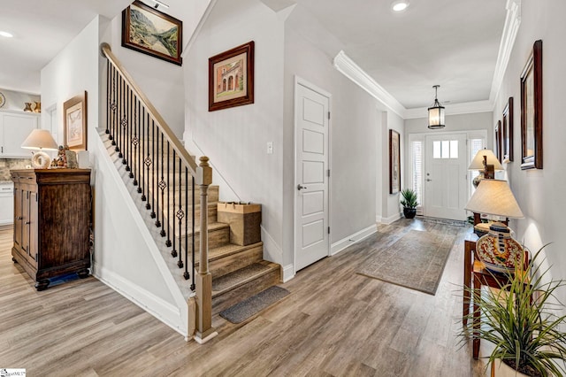 foyer entrance featuring ornamental molding and light wood-type flooring