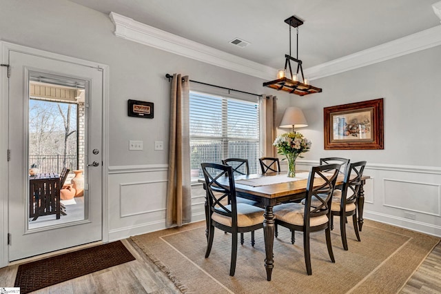 dining space with crown molding, hardwood / wood-style flooring, and a healthy amount of sunlight