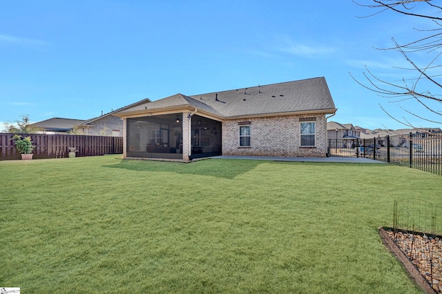 rear view of house featuring a yard and a sunroom