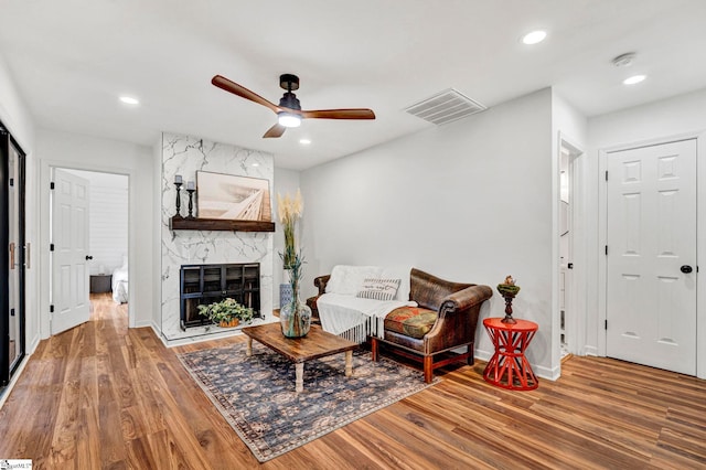 living room featuring hardwood / wood-style flooring, a high end fireplace, and ceiling fan